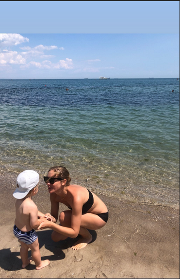 Стройная Катя Осадчая в купальнике релаксирует с сыном на пляже